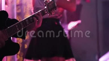吉他手演奏的特写镜头在他的乐器上直播，在一个乐队的背景上有女声歌手。
